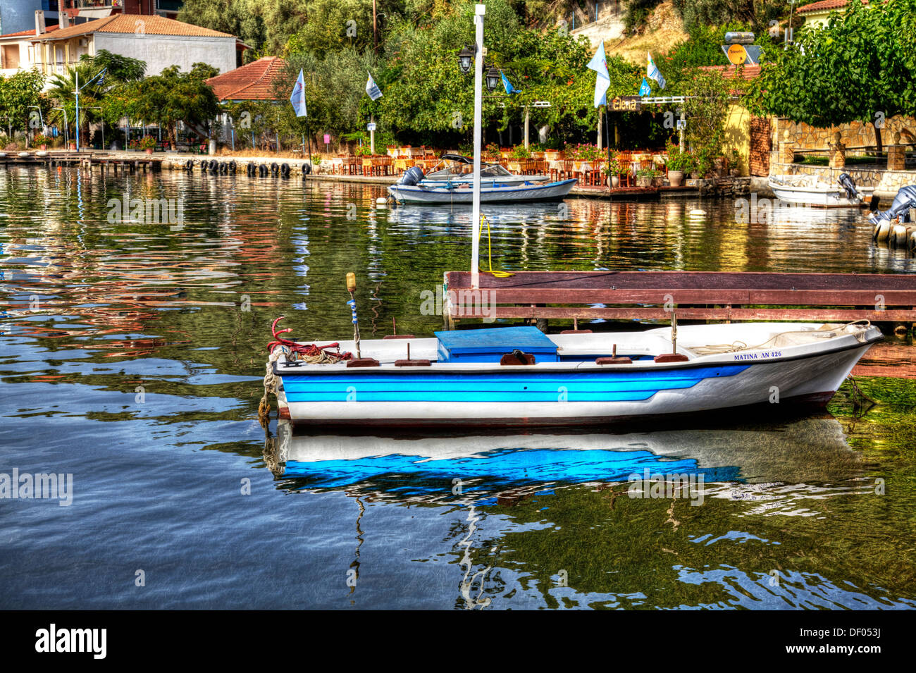 Traditional wooden fishing boat moored up at tavernas in Geni Lefkada Lefkas Greek Island Greece Stock Photo