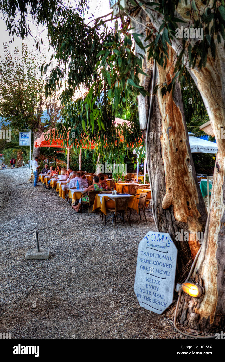 Toms beach side Taverna restaurant diners eating at tables on sand Nidri Nydri Lefkada Lefkas Greek Island Greece Stock Photo