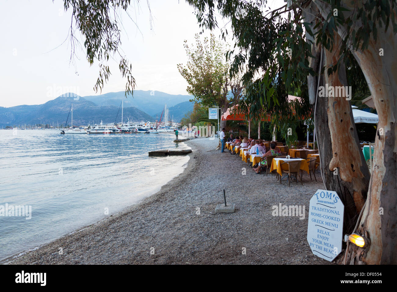 Toms beach side Taverna restaurant diners eating at tables on sand Nidri Nydri Lefkada Lefkas Greek Island Greece Stock Photo