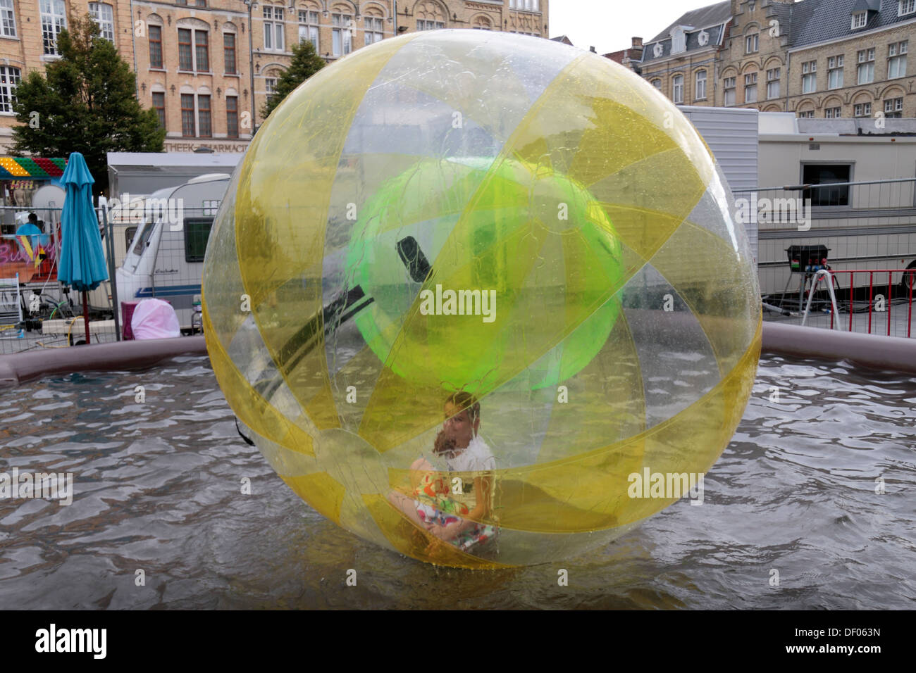 Girl inside massive plastic ball (zorb) on water (zorbing) in the Grote Market, in the centre of Ieper (Ypres), Belgium. Stock Photo