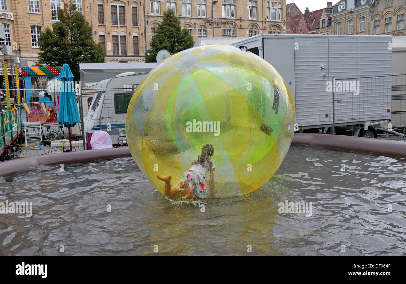Girl inside massive plastic ball (zorb) on water (zorbing) in the Grote Market, in the centre of Ieper (Ypres), Belgium. Stock Photo