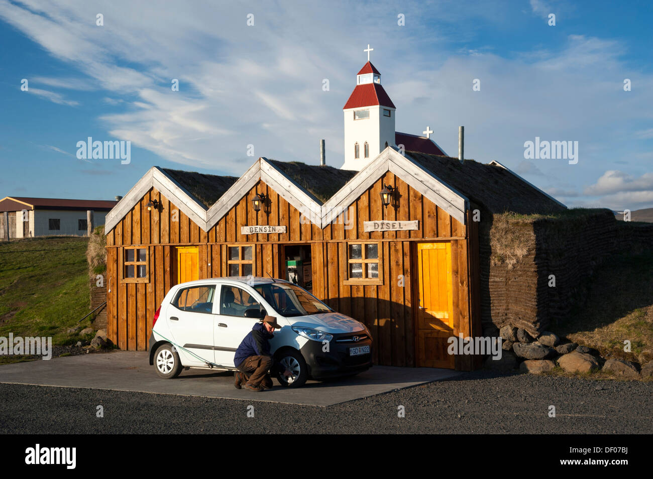 Man kneeling next to a car checking the tyre pressure, petrol station