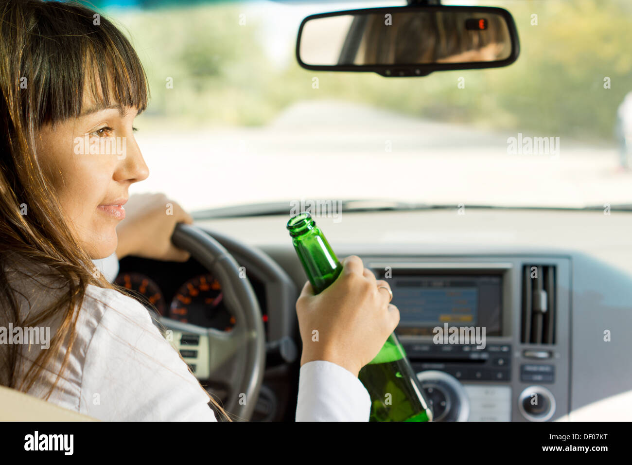 Drunk female driver drinking alcohol from the bottle turning and