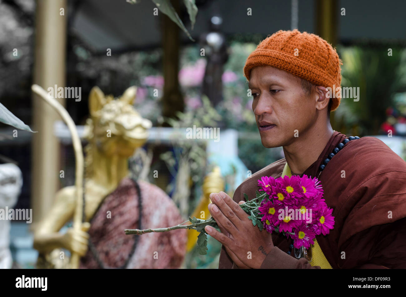 Buddhist monk holding flowers during a morning alms collection, temple and monastery of Wat Phra Archa Thong or Golden Horse Stock Photo