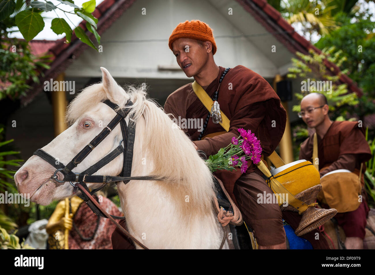 Buddhist monk on horseback collecting alms in the morning, temple and monastery of Wat Phra Archa Thong or Golden Horse Temple Stock Photo