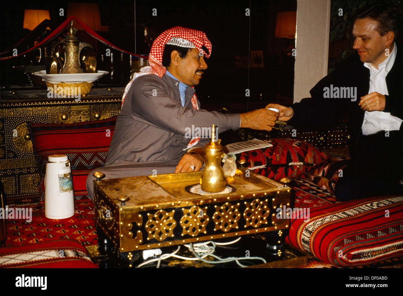 Kuwait Man Offering Coffee to english man Brass Coffee Pot Stock Photo