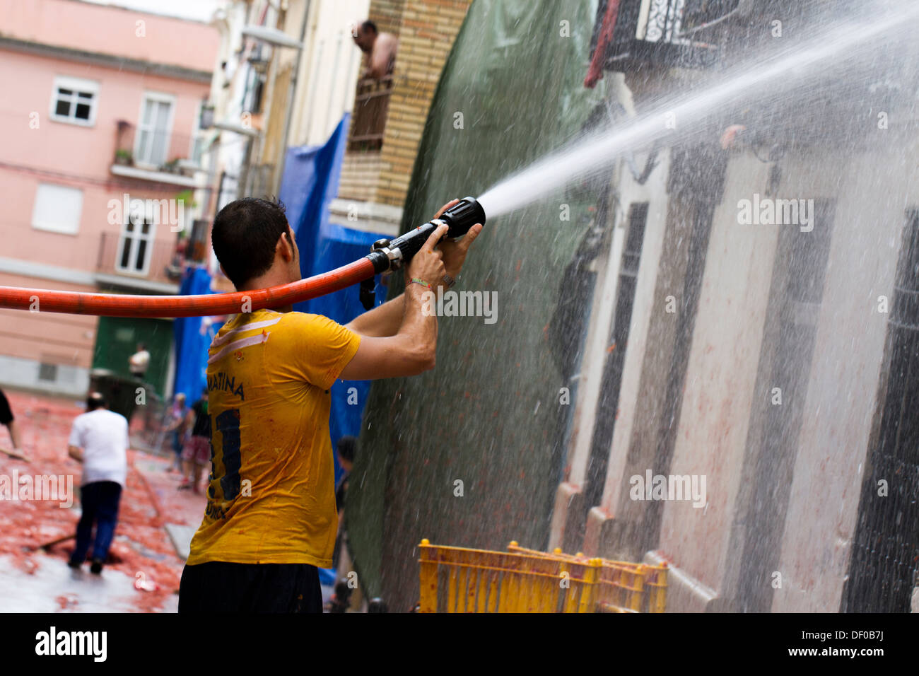 Men Spraying fire hose to clean up after Tomatina Stock Photo Alamy