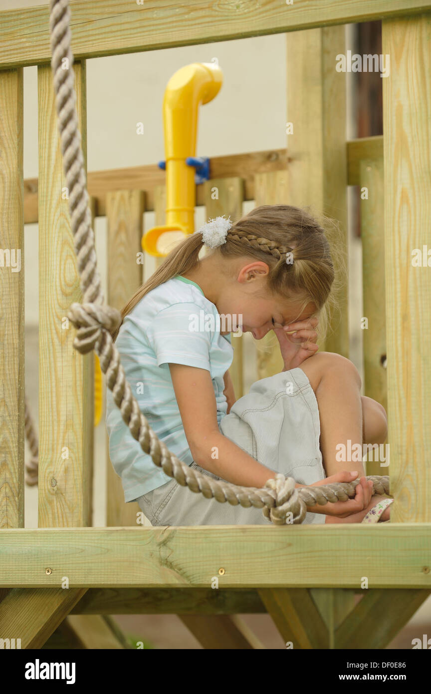 Crying 7-year-old girl, injured her foot climbing a rope on a playground Stock Photo