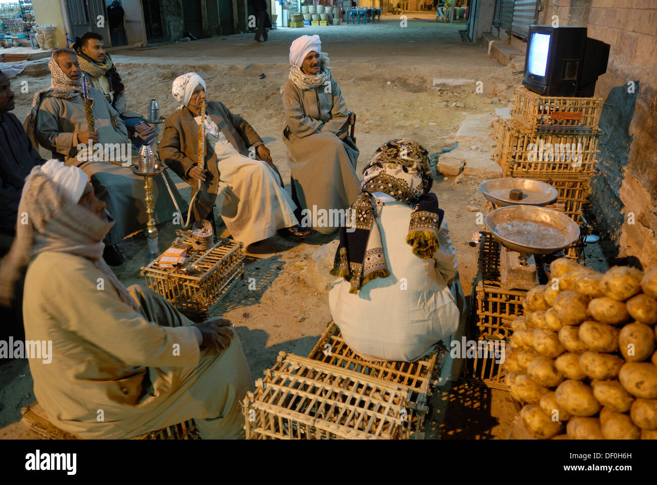 Egyptian men with hookah watching television on the street, night scene