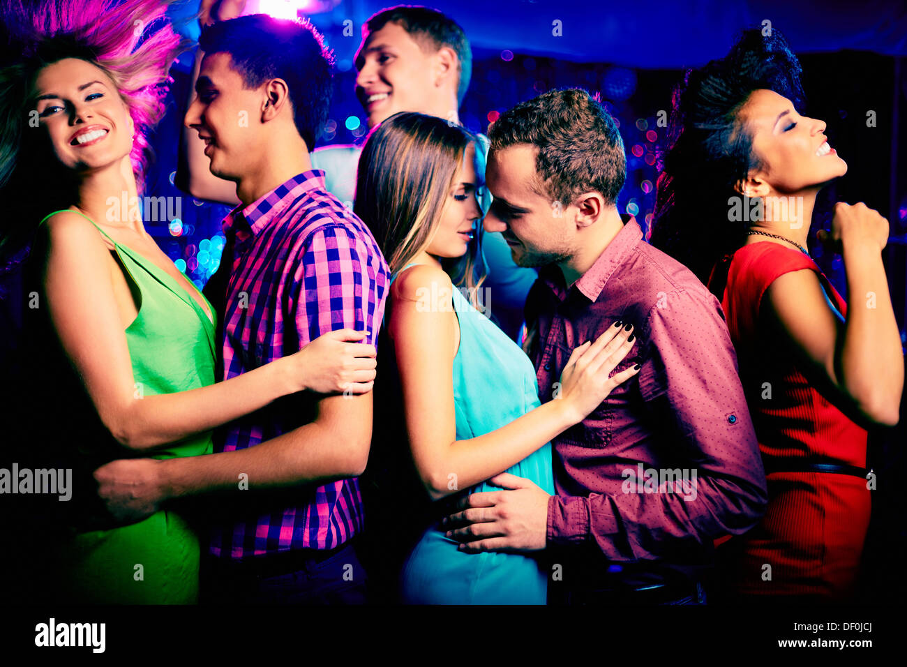 Happy young couple at disco surrounded by their dancing friends Stock ...