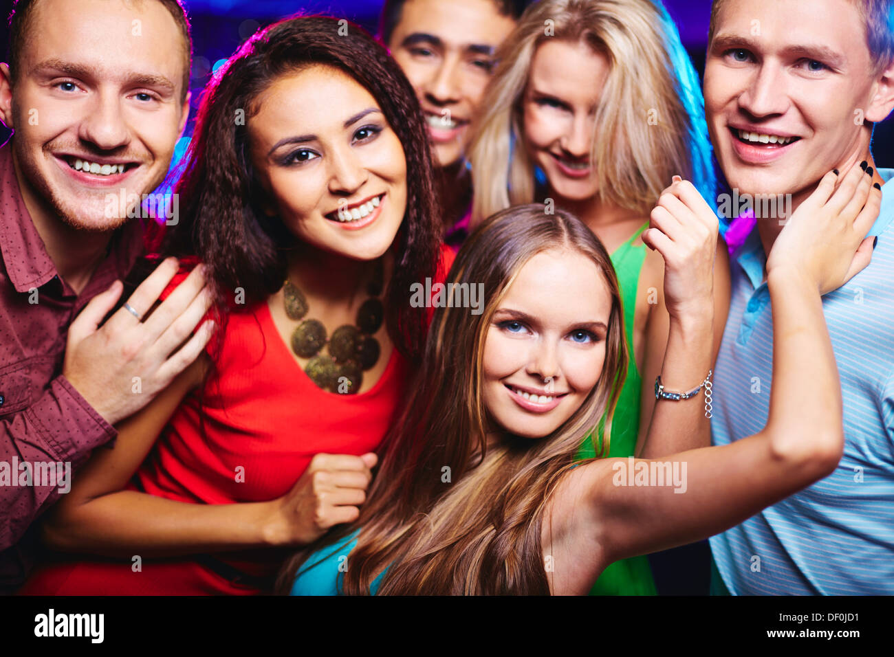 Portrait of happy friends cheering up and looking at camera at party Stock Photo