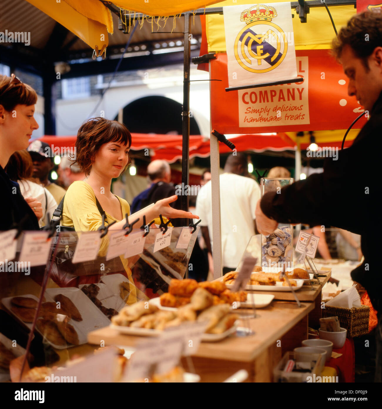 Customer buying homemade snacks at Greenwich Market stall, London