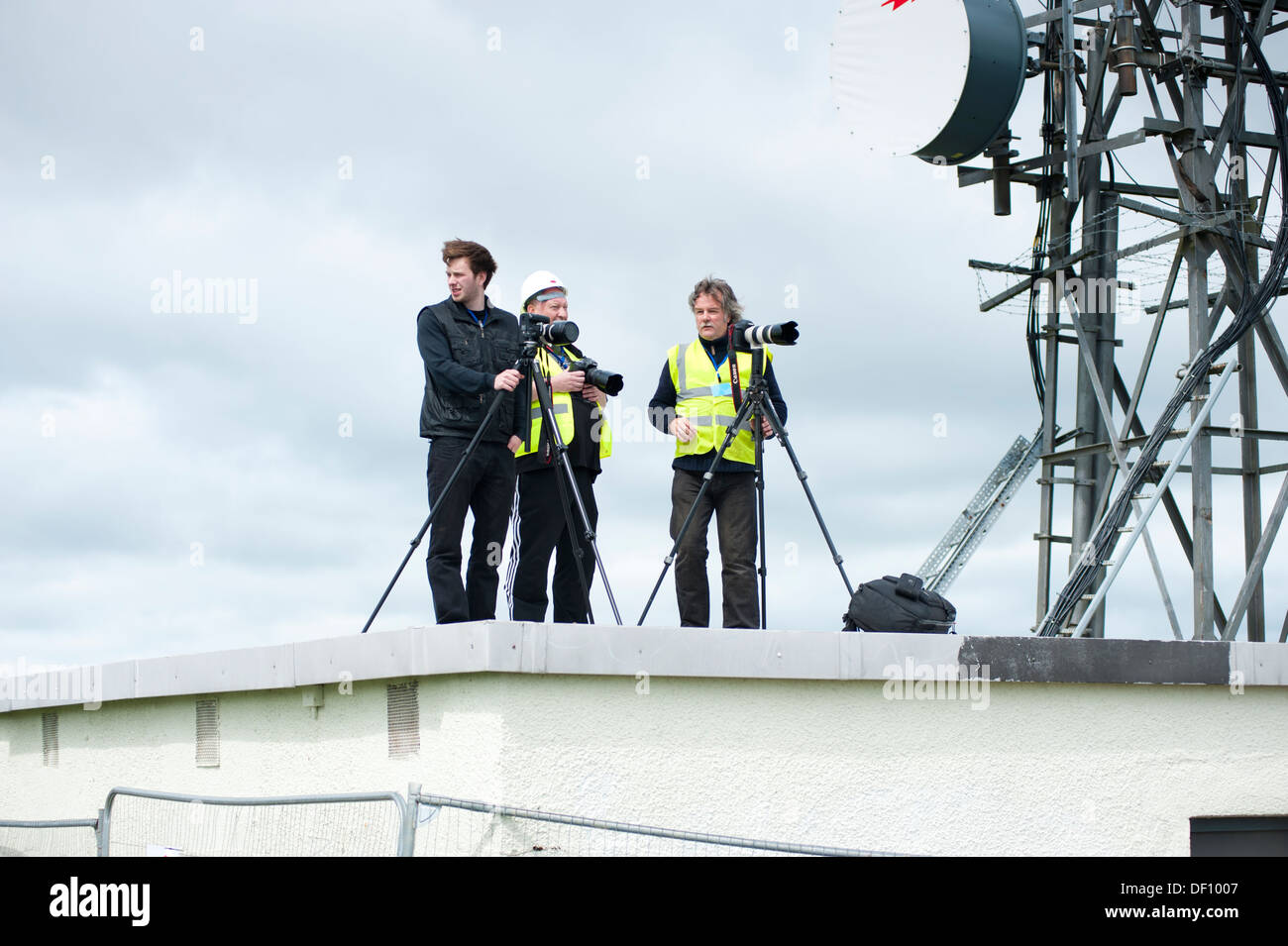 Three photographers on a roof with large antenna telecom mast Stock Photo