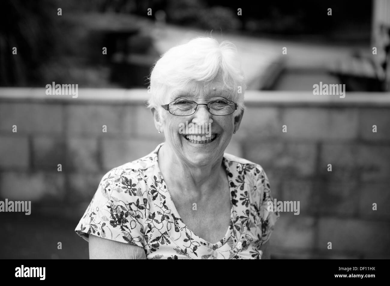 Elderly lady smiling to camera wearing glasses black and white Stock Photo