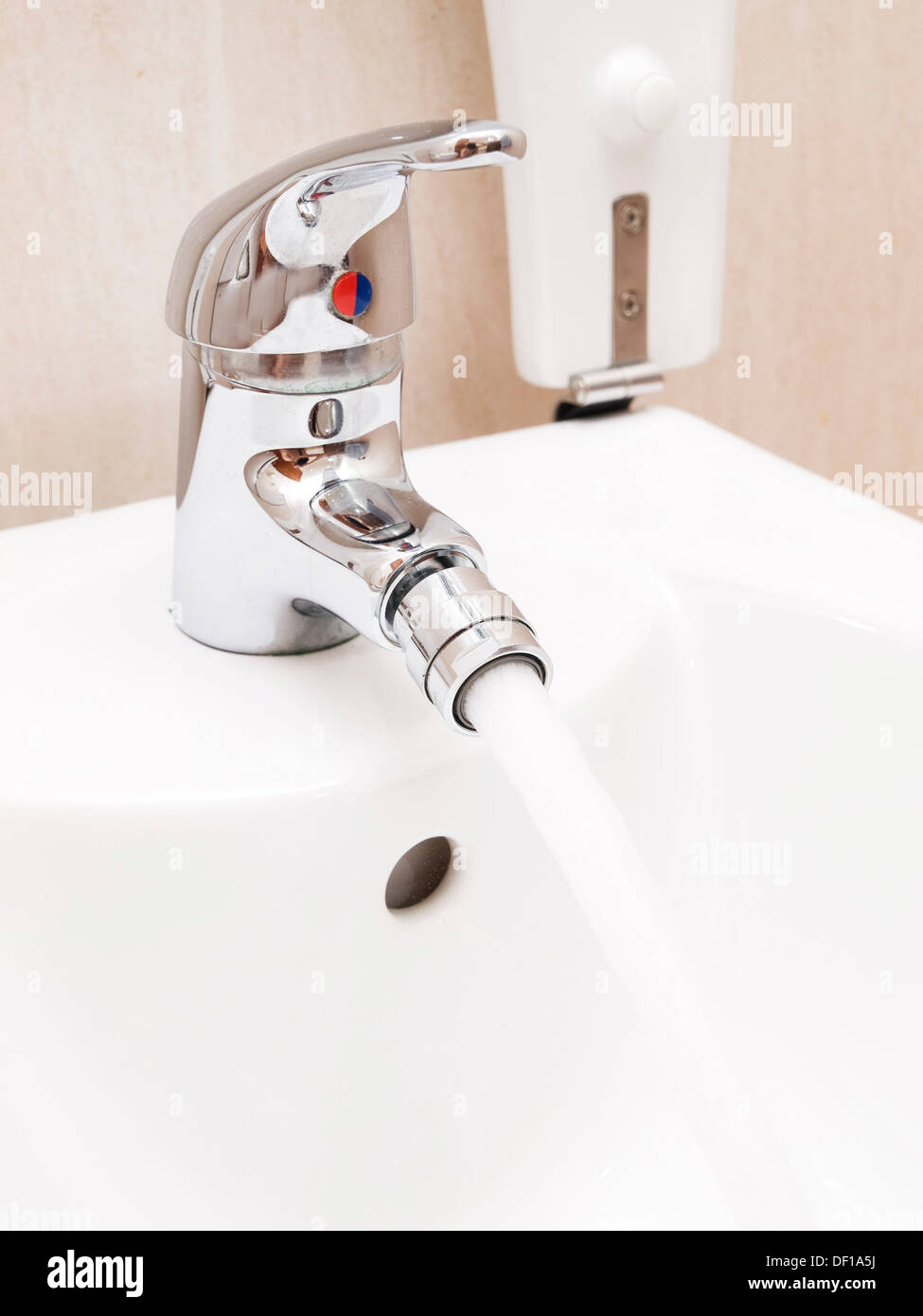Chrome mixer tap with water in a bathroom Stock Photo