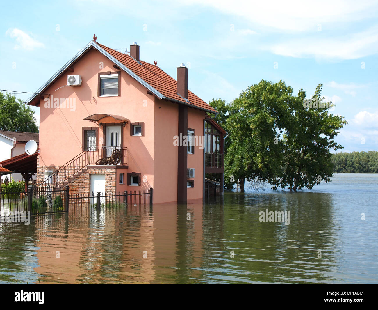 big flooded house with blue sky and white clouds in high water Stock Photo