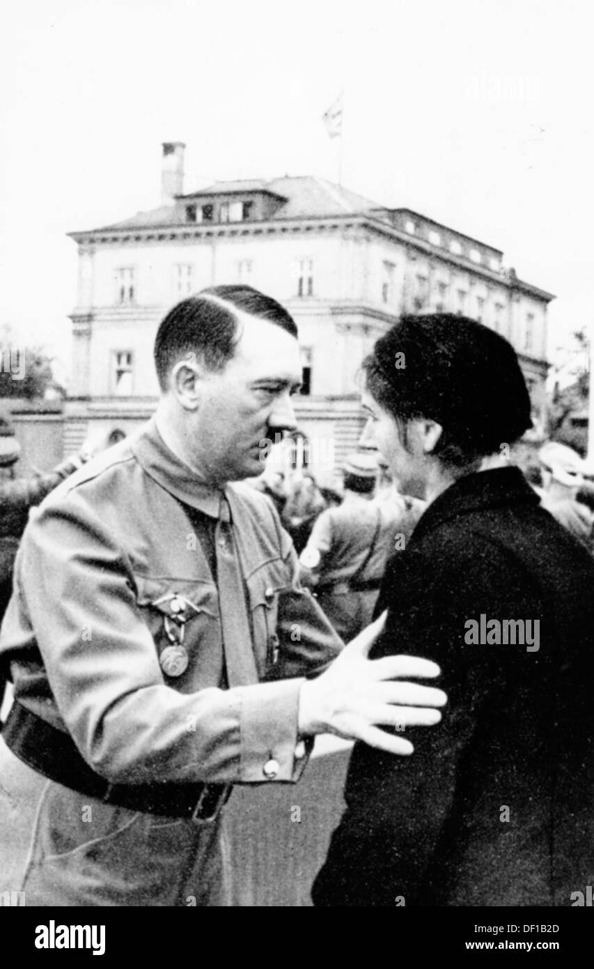 The image from the Nazi Propaganda! shows Adolf Hitler on the occasion of the anniversary of the Beer Hall Putsch of 9 November 1923, in Munich, Germany, on 9 November 1935. Here, he talks to the woman of a person killed during the march to the Feldherrenhalle in 1923. In the background, the 'Braune Haus' (Brown House). Fotoarchiv für Zeitgeschichte Stock Photo
