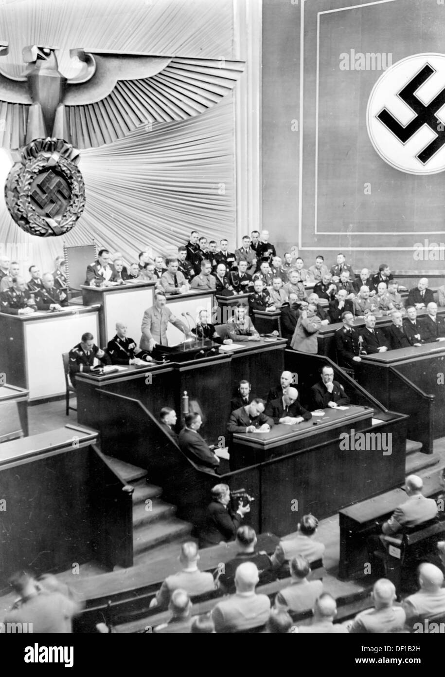 The image from the Nazi Propaganda! shows Reich Chancellor Adolf Hitler delivering a speech in the Kroll Opera House in Berlin, Germany, 18 March 1938. The speech dealt with, among other topics, the annexation of Austria by the German Reich. To the right, the Austrian government headed by Arthur Seyß-Inquart is pictured, to the left, the German Reich government. Fotoarchiv für Zeitgeschichte Stock Photo