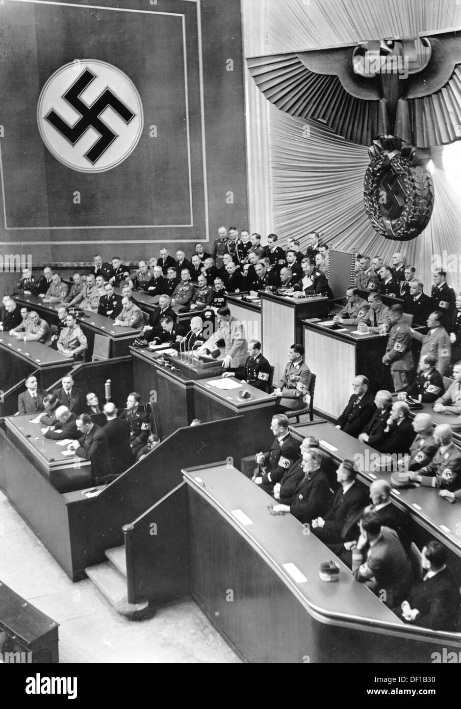 The image from the Nazi Propaganda! shows Reich Chancellor Adolf Hitler delivering a speech to the Reichstags in the Kroll Opera House in Berlin, Germany, 18 March 1938. The speech dealt with, among other topics, the annexation of Austria by the German Reich. To the right, the Austrian government headed by Arthur Seyß-Inquart is pictured, to the left, the German Reich government. Fotoarchiv für Zeitgeschichte Stock Photo