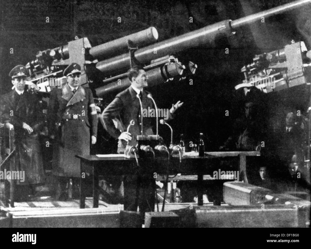 Reich Chancellor Adolf Hitler delivers a speech in front of an antiaircraft gun to the workers of an arms factory. To the left: Propaganda Minister Joseph Goebbels and Head of the German Labor Front Robert Ley. Fotoarchiv für Zeitgeschichte Stock Photo