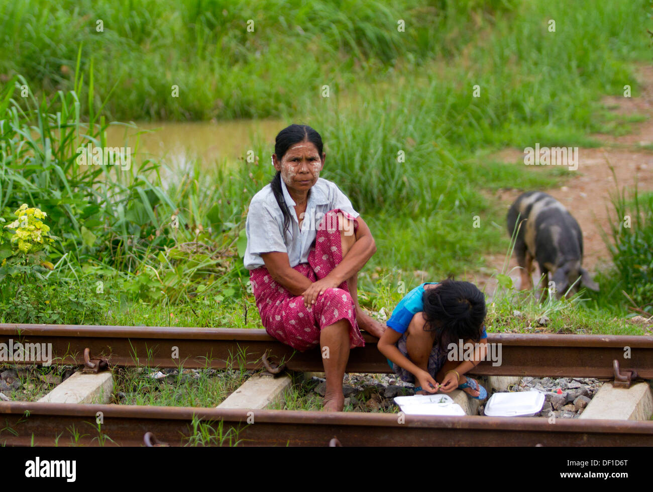 People sit on the railroad tacks outside Kinpun, Burma. Stock Photo
