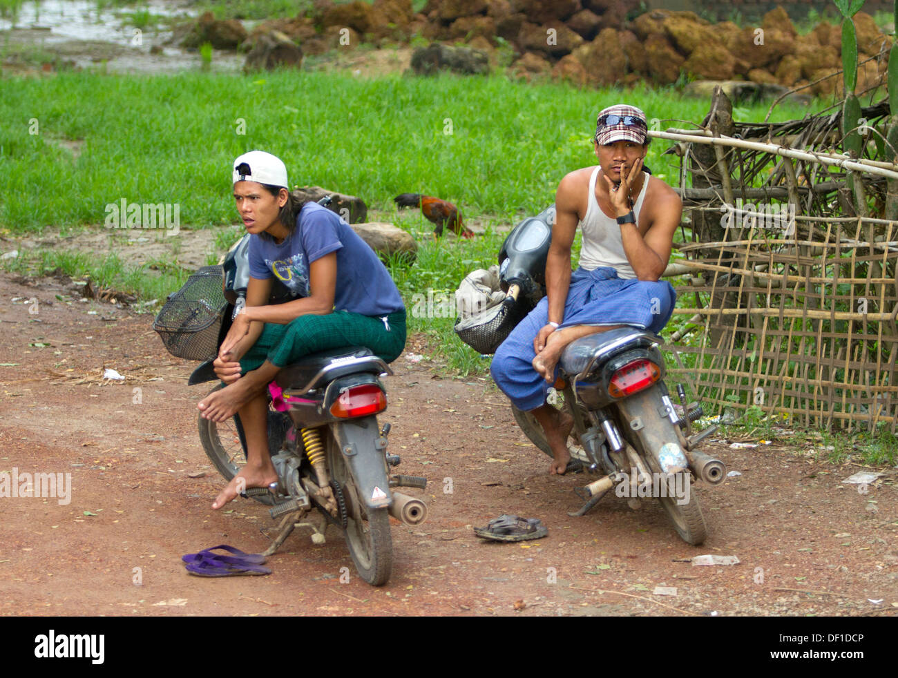 Men sit on motorbikes outside Kinpun, Burma. Stock Photo