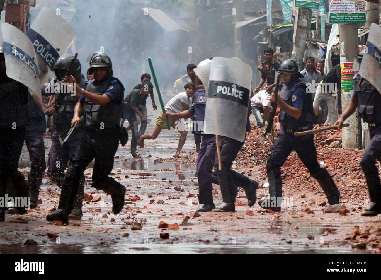 Narayanganj, Bangladesh. 26th Sep, 2013. Bangladeshi police officials take cover as striking garment workers throw stones during a protest in Narayanganj on September 26, 2013. Most Bangladesh garment factories have reopened after five days of violent protests over wage hikes for textile workers, after the government vowed to crack down on the unrest 'with all force . Stock Photo