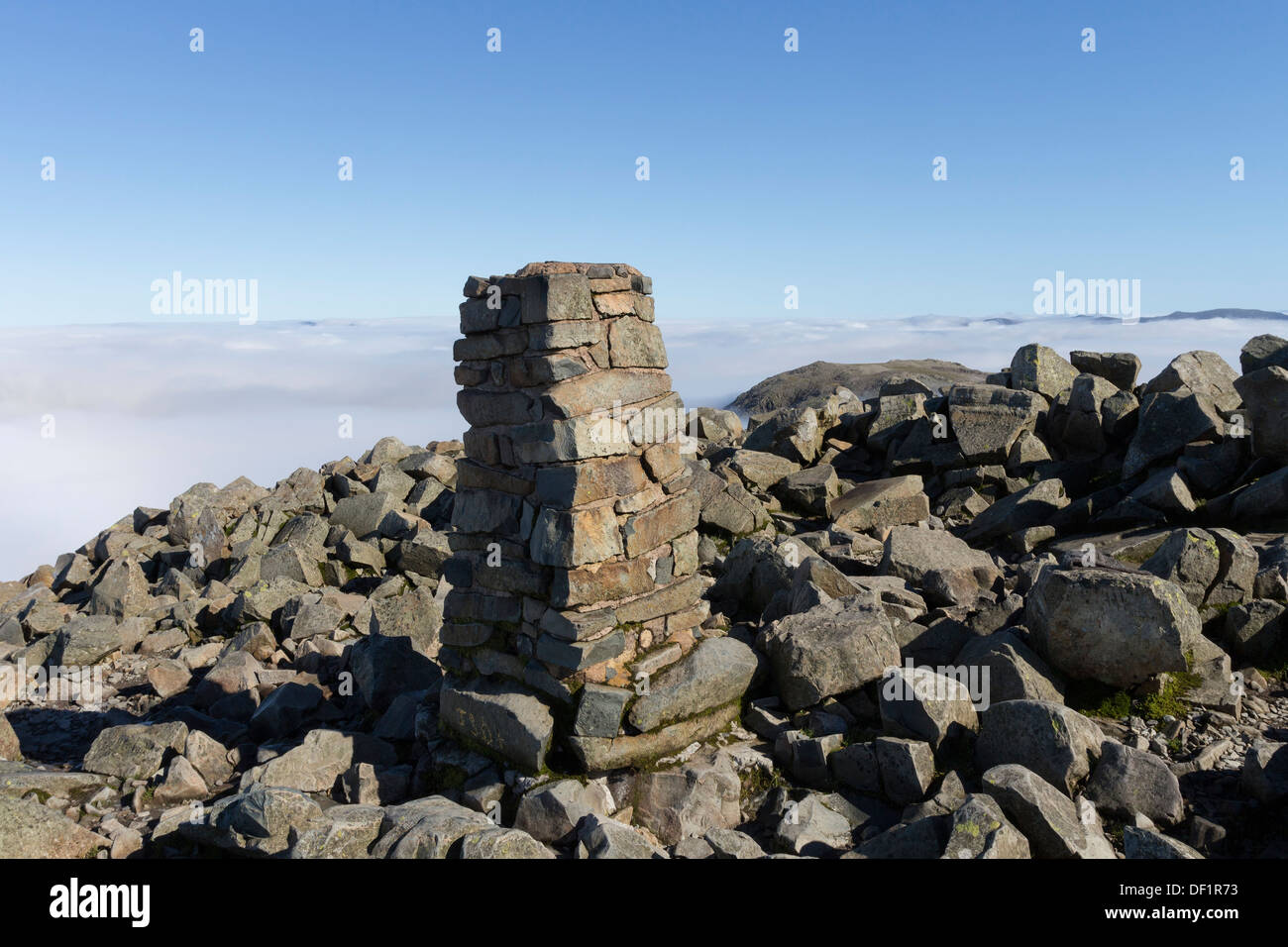 The Summit Trig Point on Scafell Pike with Clouds Created by a Temperature Inversion Behind Lake District Cumbria UK Stock Photo