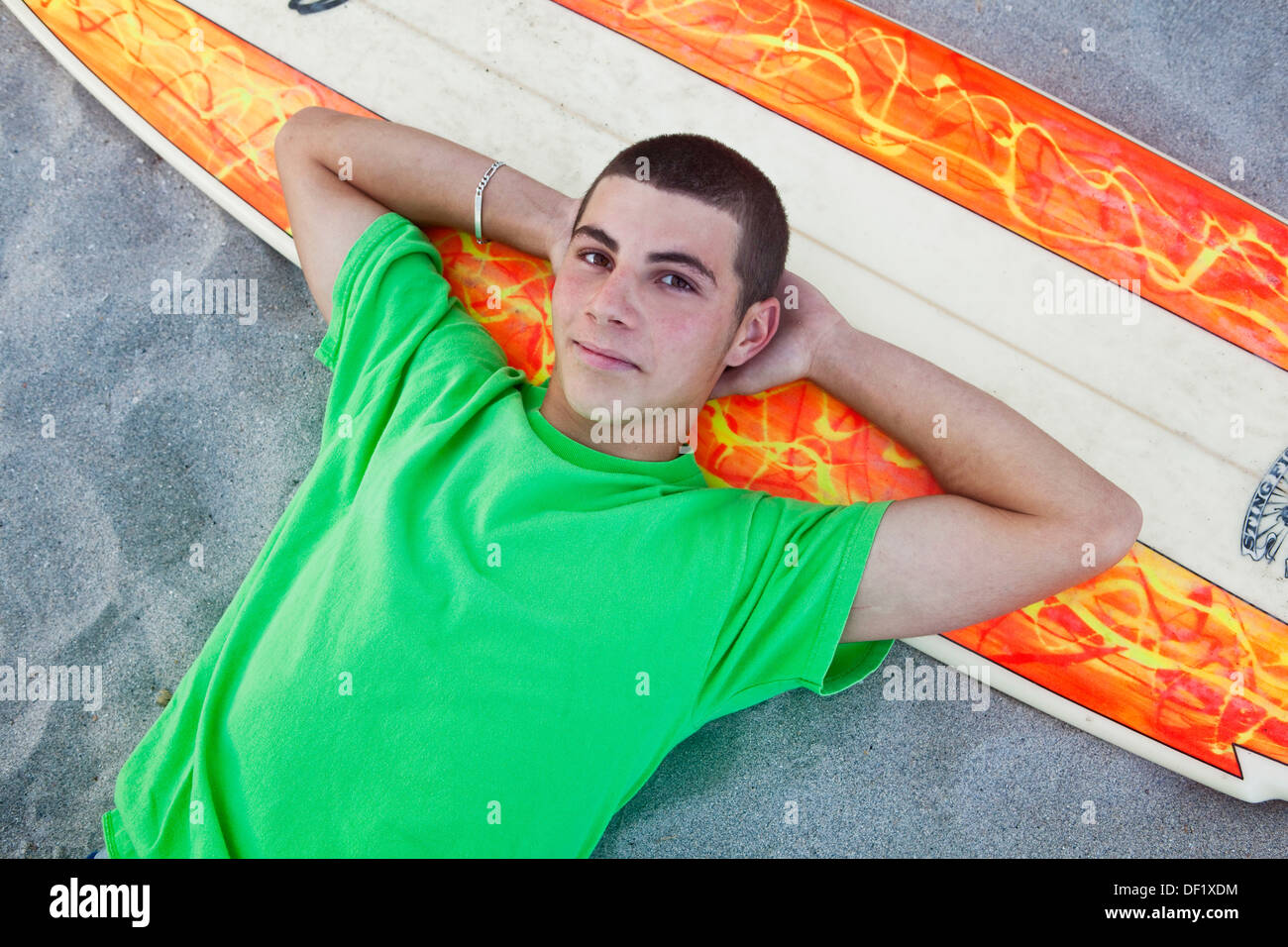 teen lying down on the beach with surfboard Stock Photo - Alamy