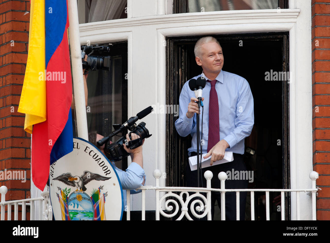 Julian Assange addresses the media and supporters while British policemen stand outside the Ecuadorian Embassy in London, Britai Stock Photo