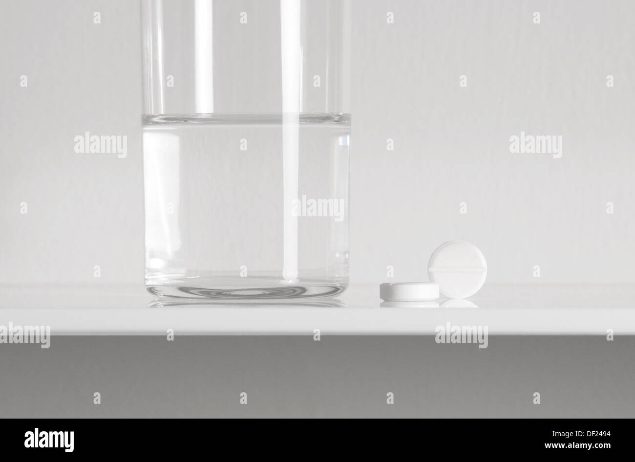aspirin tablets and glass of water on white shelf Stock Photo