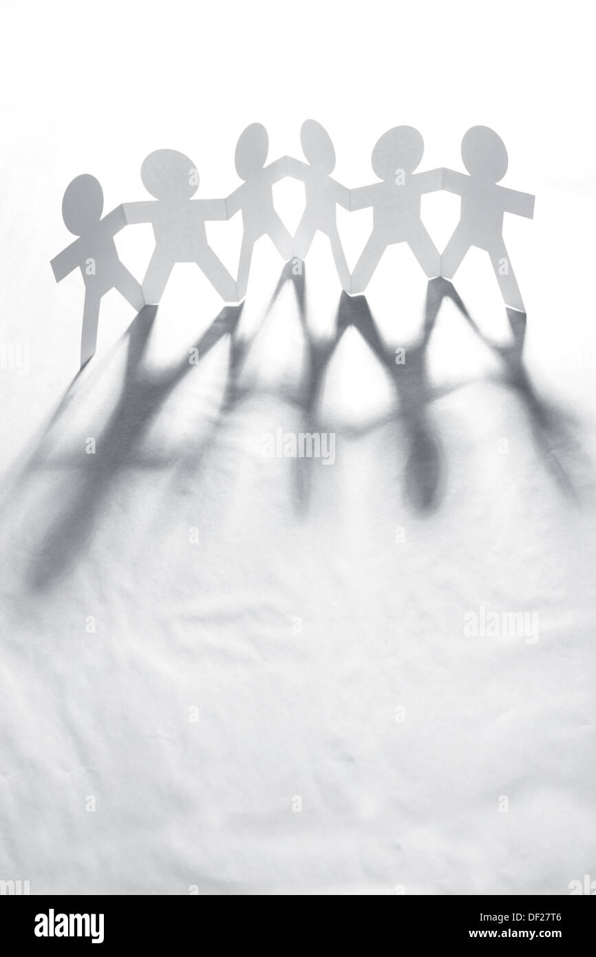 Team of six paper doll people holding hands. Teamwork concept Stock Photo