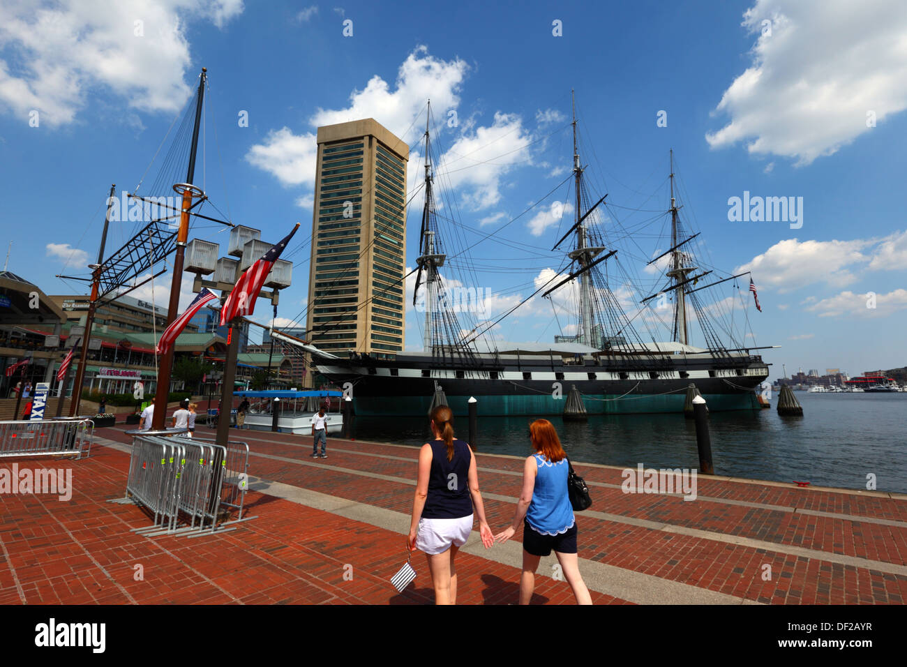 Female tourists, USS Constellation historic sailing ship, World Trade Center building in background, Inner Harbor, Baltimore City, Maryland, USA Stock Photo