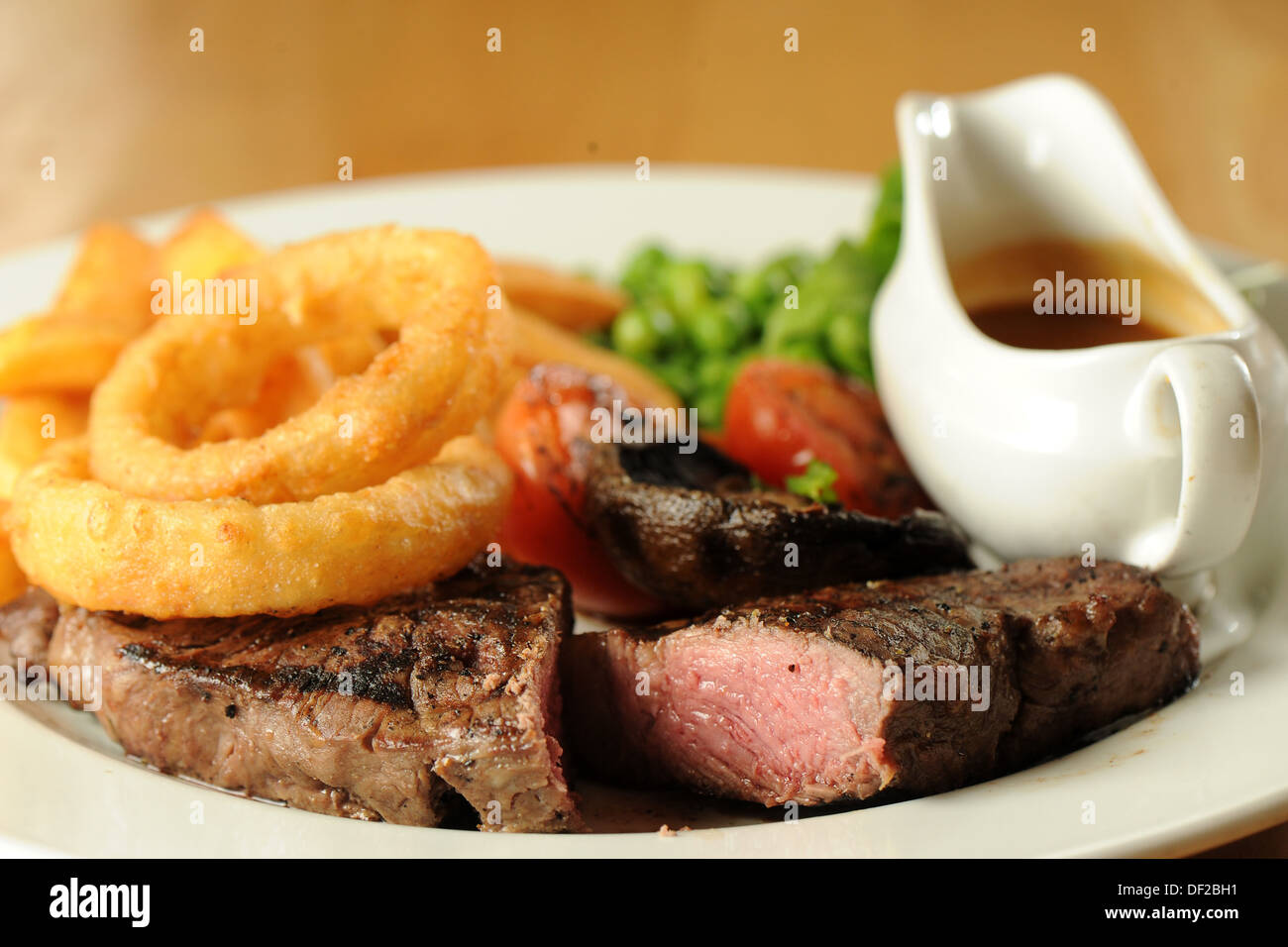 Traditional pub food sirloin steak, onion rings and peas Stock Photo