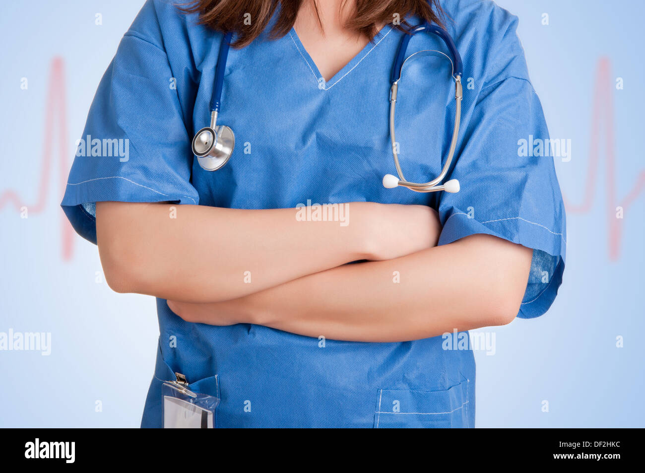 Young female doctor with scrubs and a stethoscope and arms crossed, isolated in white Stock Photo