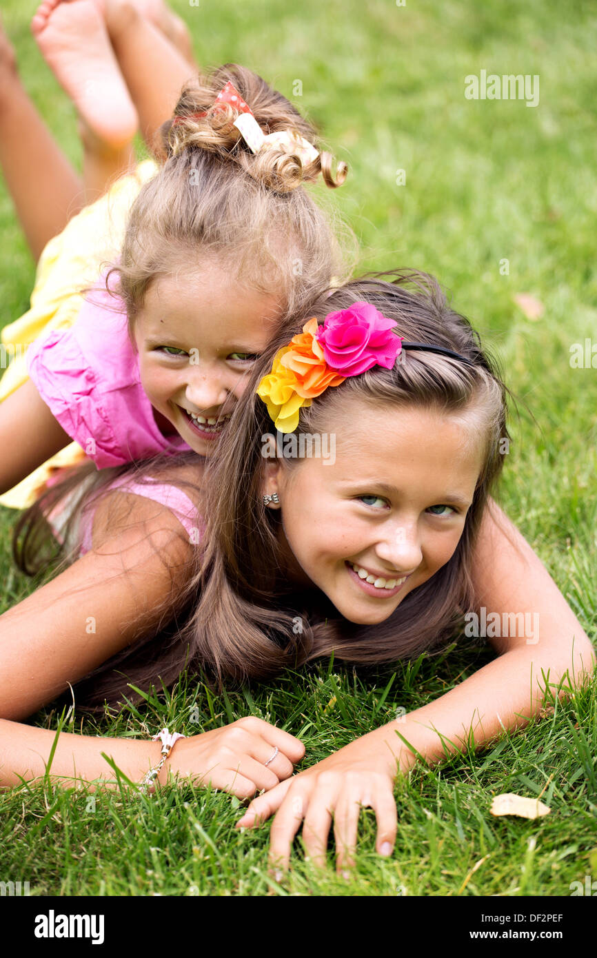 Two smiling girls playing on the summer green grass Stock Photo - Alamy