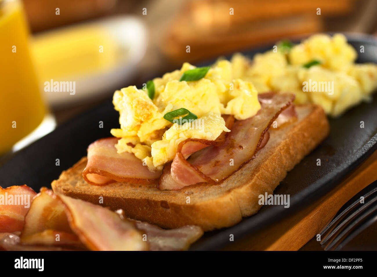 Fried bacon and scrambled egg on toast bread (Selective Focus, Focus on the front of the shallot in the front) Stock Photo