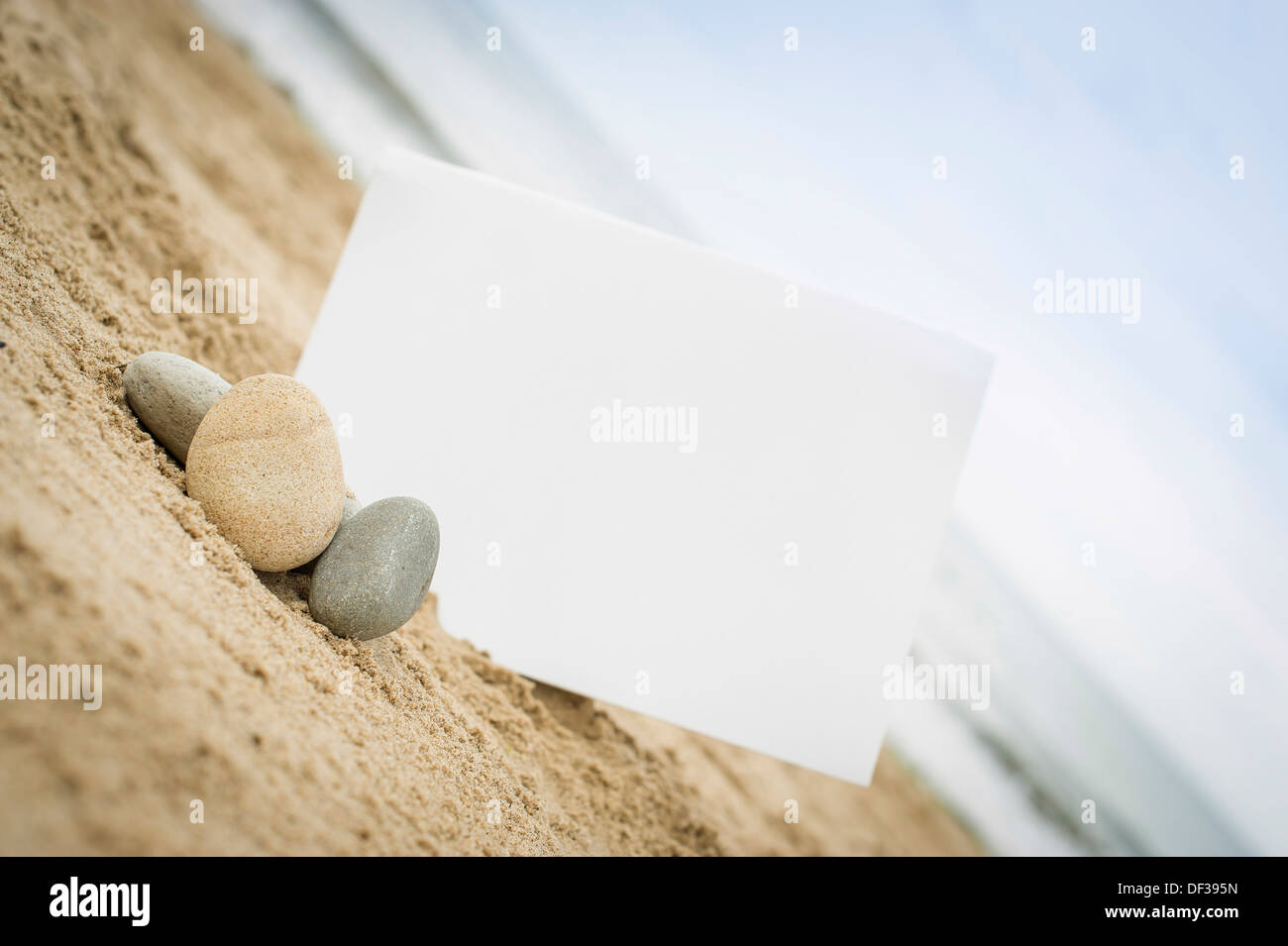 Blank white sign on a sand beach with stones and pebbles Stock Photo