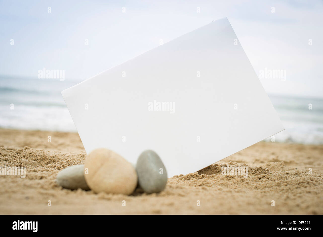 Blank white sign on a sand beach with stones and pebbles Stock Photo