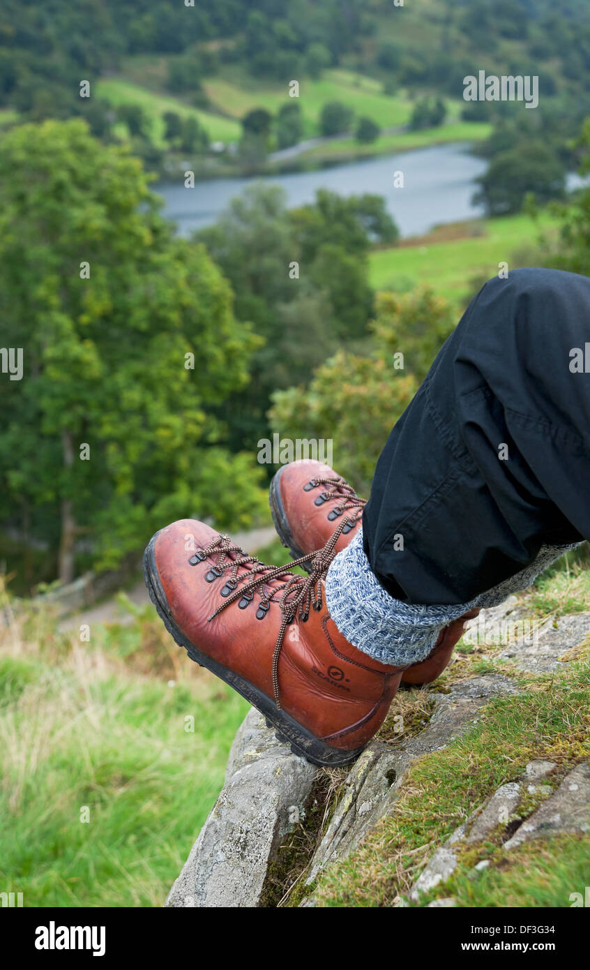 Close up of person walker man wearing walking boots sat sitting on a fell cliff edge in the Lake District National Park England UK Britain Stock Photo