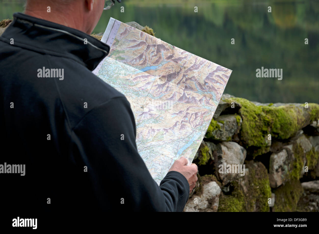 Close up of man walker tourist visitor reading holding map of the Lake District National Park Cumbria England UK United Kingdom GB Great Britain Stock Photo