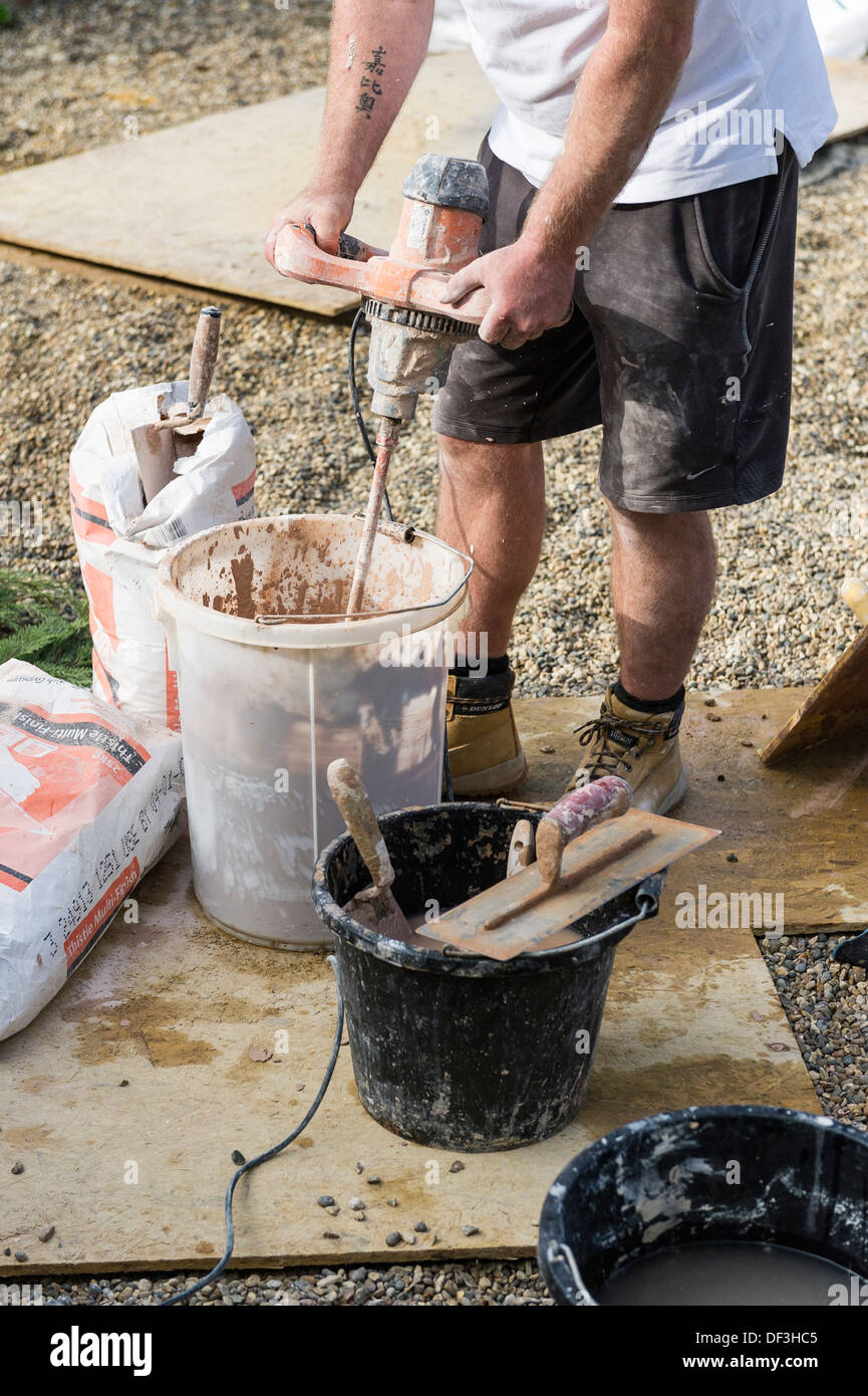 A builder using a powered plaster mixer Stock Photo Alamy