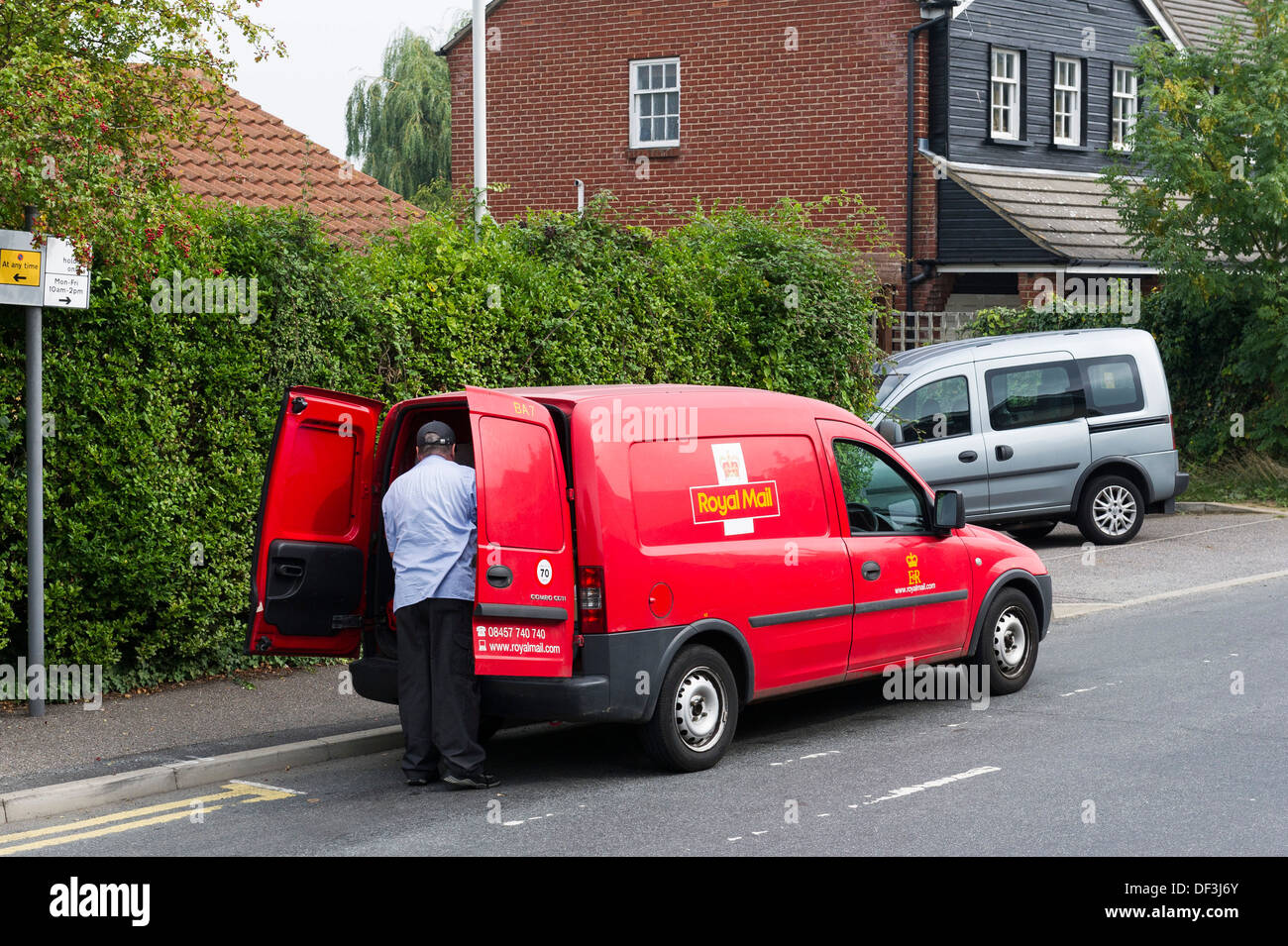 A Royal Mail worker emptying his van. Stock Photo