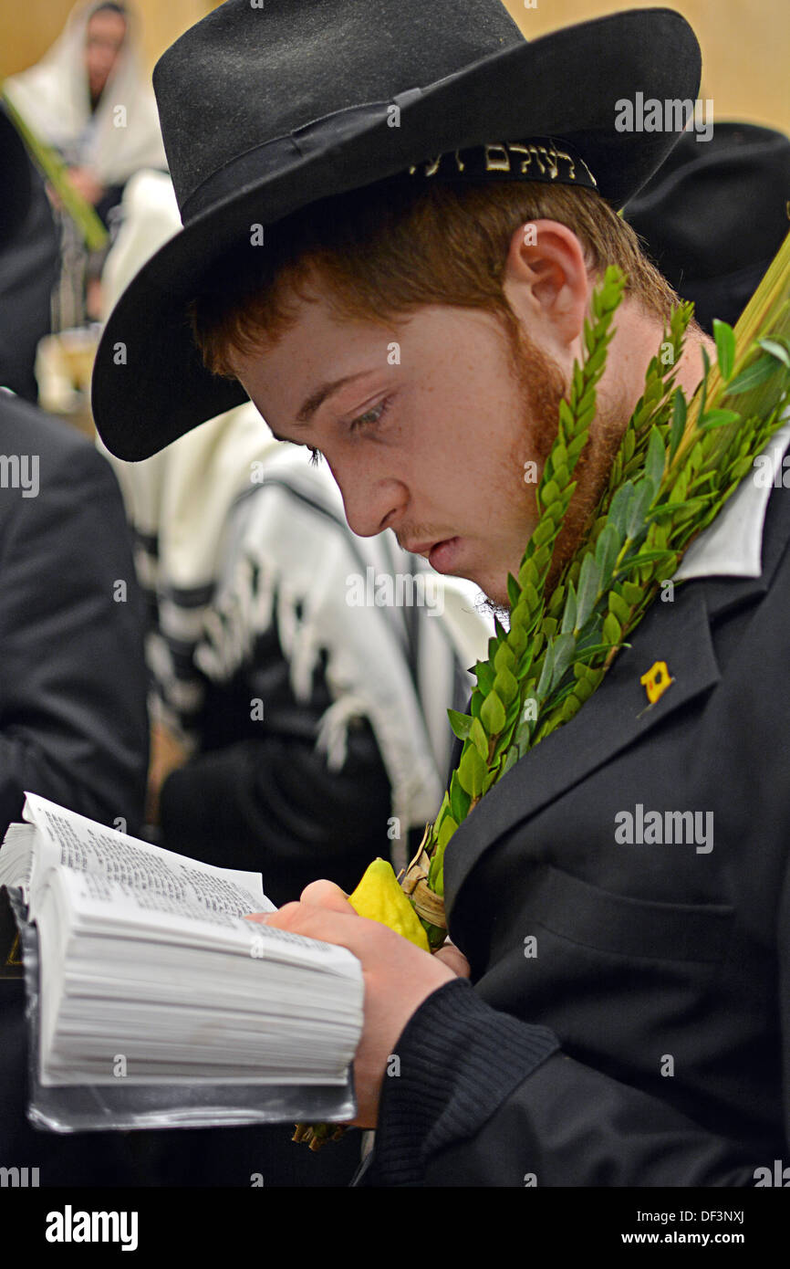 A religious Jewish young man holding an esrog and lulav at morning prayer services in Crown Heights, Brooklyn, New York Stock Photo
