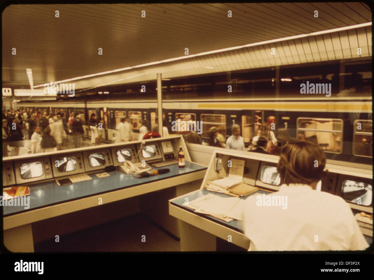 A transportation employee monitors closed-circuit TV screens at a station, allowing communication with passengers as part of security and customer service operations. Stock Photo