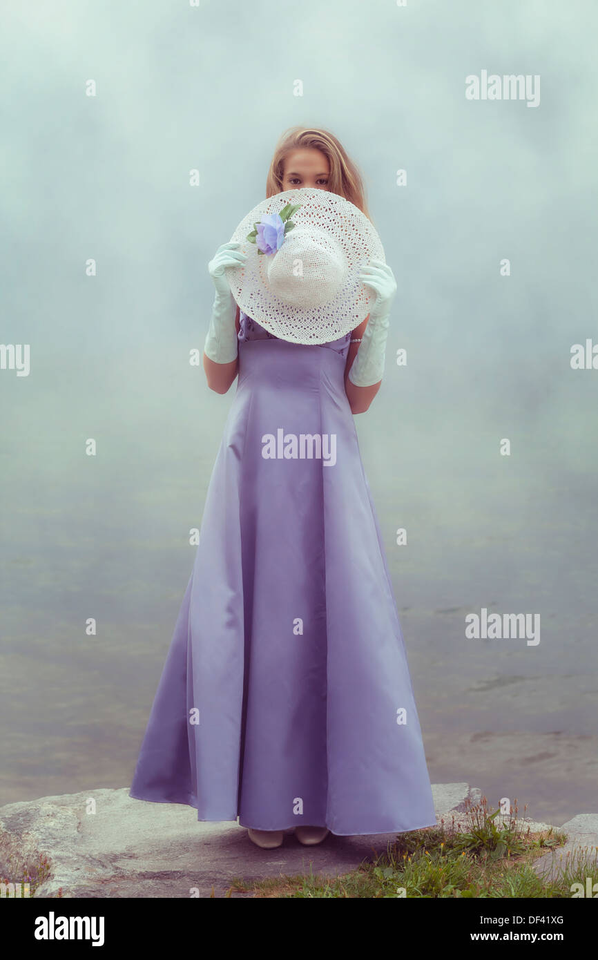 a beautiful young woman is hiding behind a white sun hat Stock Photo