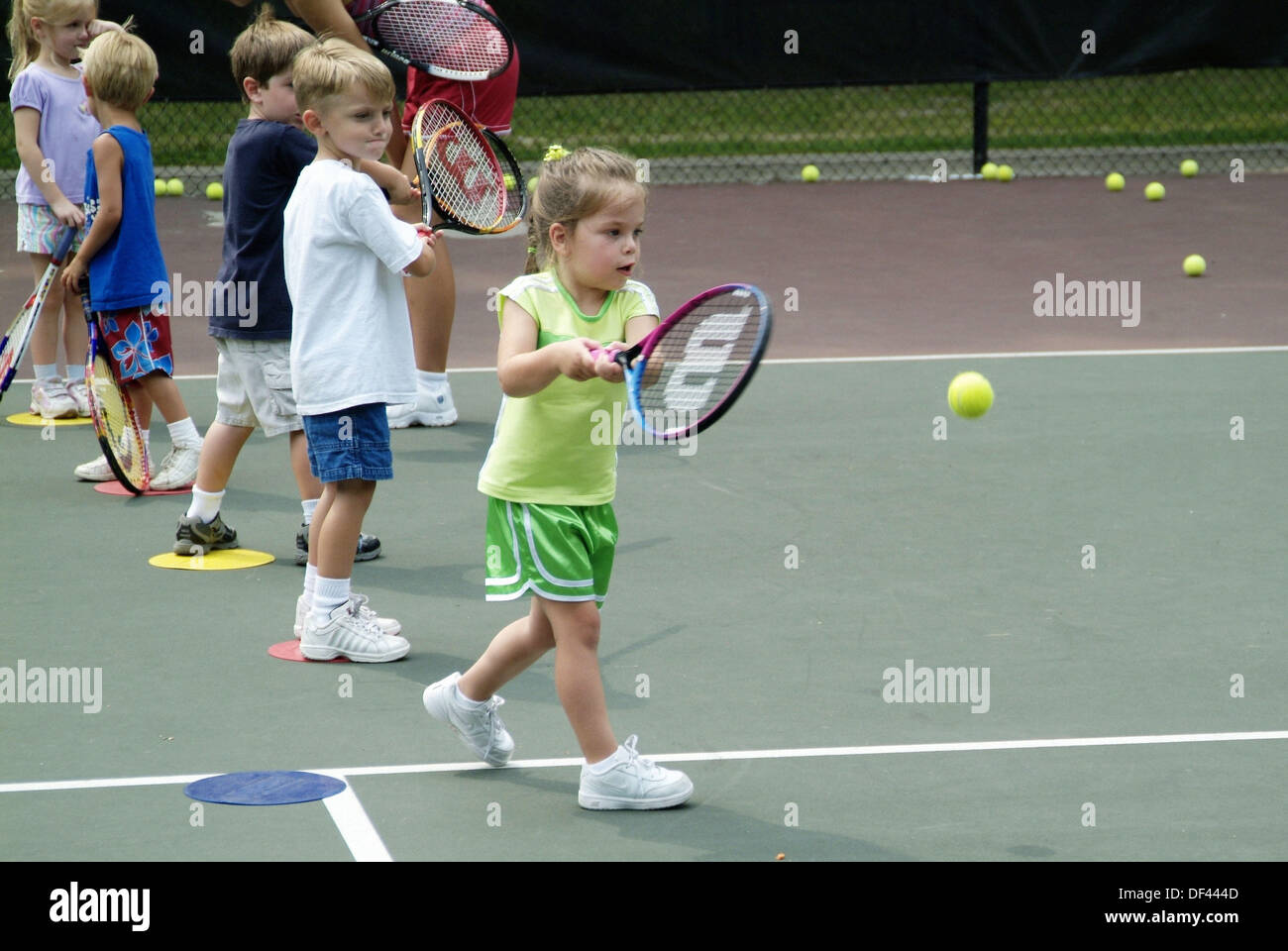 4 and 5 year old children take group tennis lessons taught by college