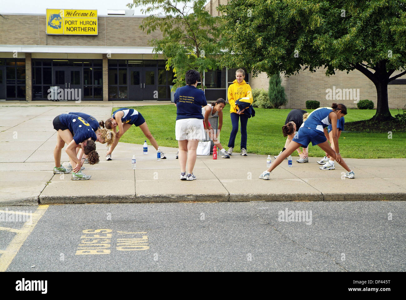 High school girls cross country running team stretches their muscles