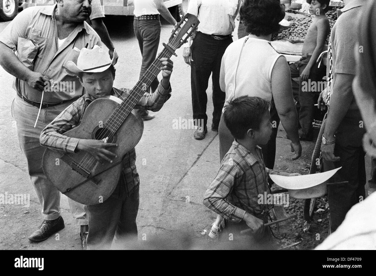 Mazatlan Mexico. Children busking in the street, brother, young sibling collecting in his hat and playing a simple wooden percussion block. Mexican state of Sinaloa 1973. HOMER SYKES Stock Photo