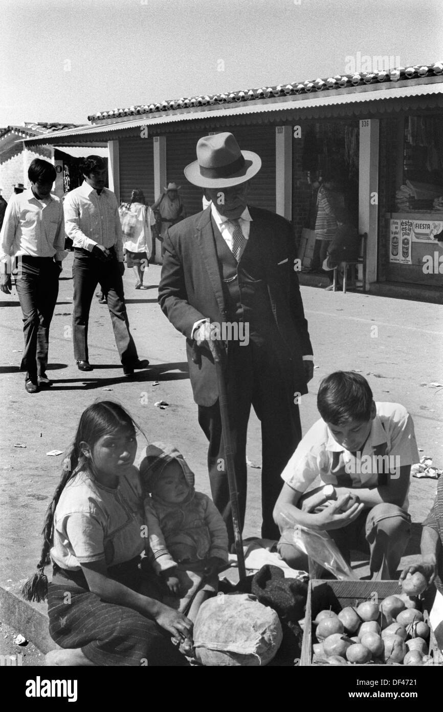 San Cristóbal de las Casas 1970s Mexico. Elderly man has servant  to buy fruit for him from Indigenous young Indian girls with a baby selling in the daily market. Mexican State of Chipas  1973 HOMER SYKES Stock Photo